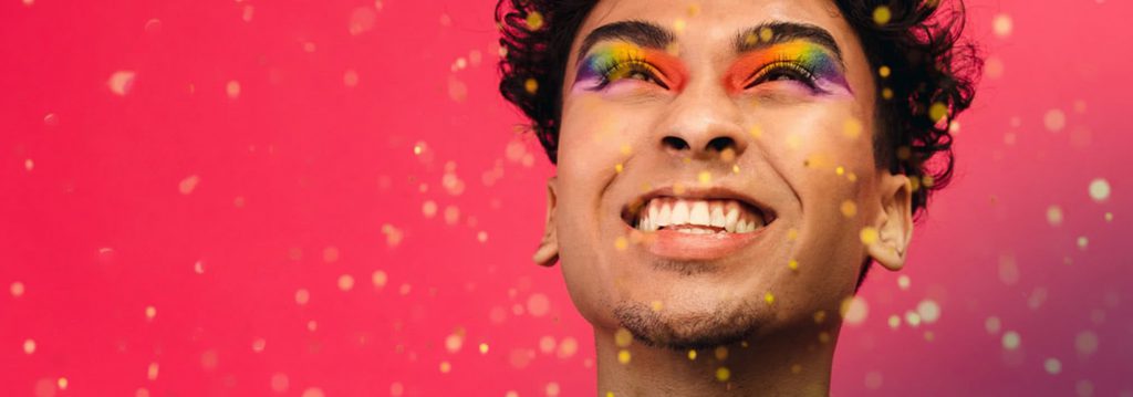 Close-up of smiling man with rainbow eye makeup